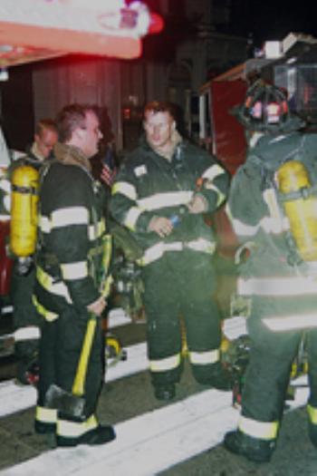 Three firefighters from the Cambridge Fire Department stand near the Mass. Ave. building where fire struck on Friday night.
