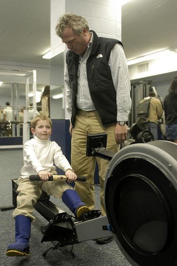 Quincy House Master Robert P. Kirshner watches as Tom Parker, the six-year-old son of Kennedy School Professor Richard Parker, tries out one of the new rowing machines in the Quincy House gym.