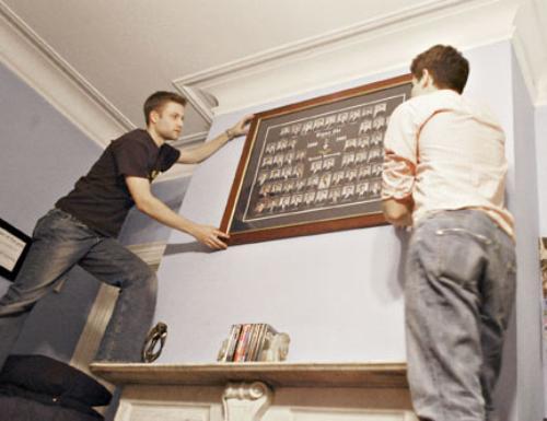 Sigma Chi President Matthew B. Salzberg ’05, left, and Recruitment Chair Alexander M. Weiss ’05 adjust a framed portrait of fraternity alums in their shared bedroom in the now-inhabited Sigma Chi house on Mass. Ave.