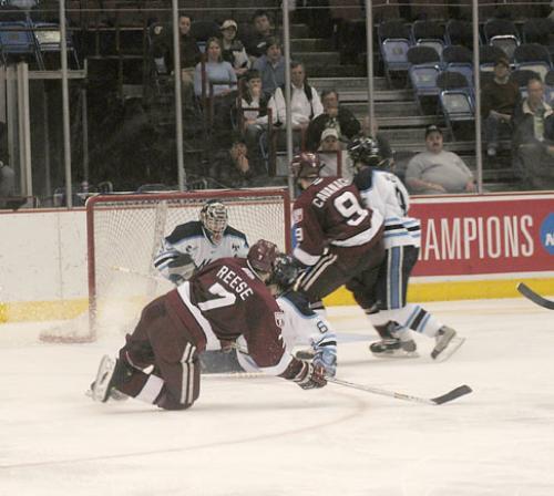 Freshman defenseman Dylan Reese (7) and junior forward Tom Cavanagh (9) crash the net in front of Maine goalie Jimmy Howard, whom the Crimson chased from the game with four goals in two periods.