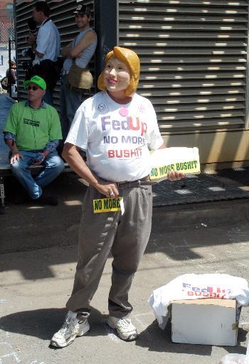 A protestor sporting a Hillary Clinton mask ridicules both the president and his challenger outside the Democratic National Convention on Monday.
