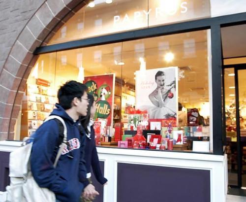 A curious windowshopper looks at the display of Papyrus, a stationery-store chain that opened Friday on JFK Street in the Square.  