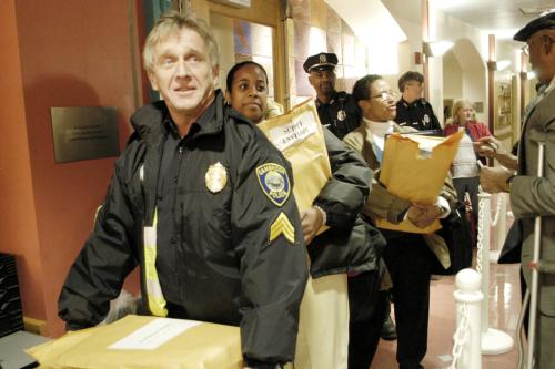 Cambridge police enter the Cambridge Senior Center with packages of ballots to be tallied. Preliminary election results for the city council and school board committee were released last night. 