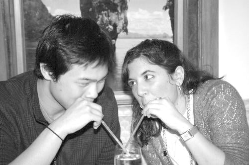 Eric and Christina exercise their lips by sipping from the same drink.