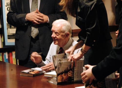 President Jimmy Carter signing copies of "Palestine: Peace Not Apartheid" at the Coop in Harvard Square Tuesday afternoon. The book drew condemnation from parts of the U.S. Jewish community, but most of the demonstrators outside the bookstore held placard