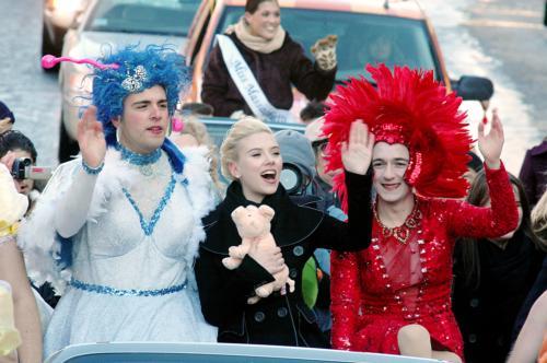Scarlett Johansson, Hasty Pudding’s Woman of the Year, waves alongside two Hasty Pudding Theatricals members in drag costumes during the annual parade down Mass. Ave. Pudding members later roasted the actress.