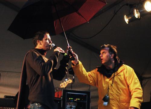Stephan Jenkins of the band Third Eye Blind performs at Yardfest Saturday evening as an event official hands him an umbrella. 