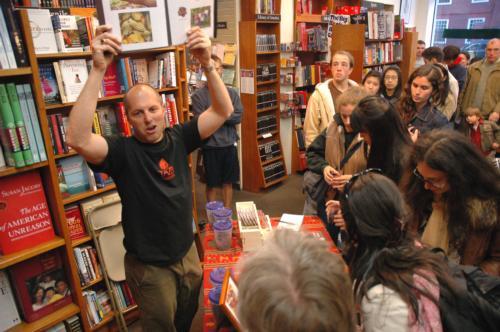 Larry Slotnick of the Somerville-based Taza Chocolate holds up a portfolio depicting the organic farming practices of the cacao farmers from which his company buys its raw materials in the Harvard Book Store last night. Eager members of the public jostled