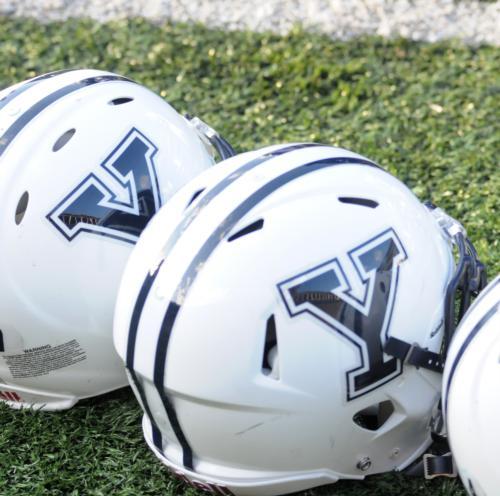 Yale helmets lie along on the sideline during a team huddle.  