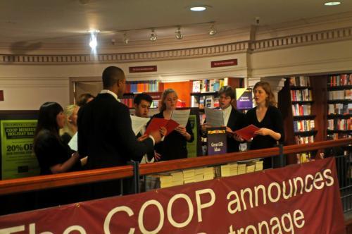 Members of Harvard’s Collegium Musicum present a selection of a cappella holiday music at the Harvard Coop on Sunday afternoon.