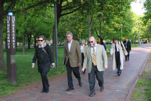 College administrators walk through Cambridge Common Monday on their way to Cabot House to discuss cost-cutting measures in the Faculty of Arts and Sciences.