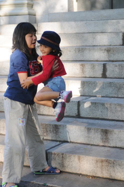 A girl helps her sister jump off the steps of University Hall yesterday afternoon.