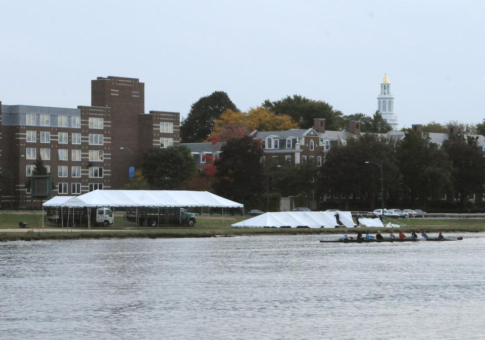 Preparations for the 45th annual Head of the Charles Regatta begin, as crew teams warm up on the river and workers raise a tent for spectators. This year's race will feature 'Reunion Villages' for participating schools' alumni.