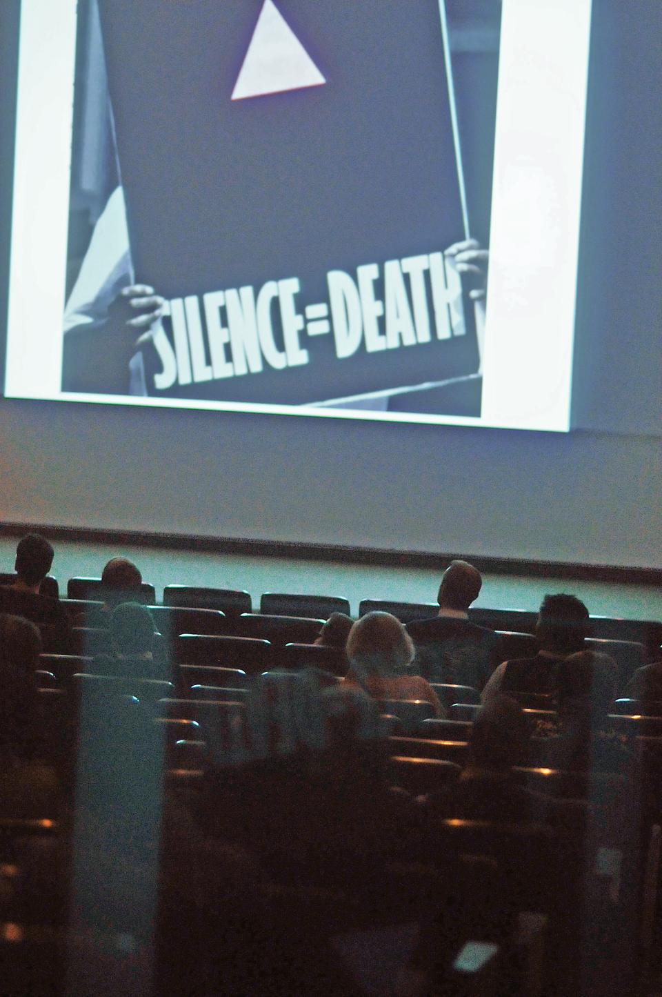 AIDS is a disease that crosses cultural boundaries, comments Philip Yenawine, co-founding director of Visual Understanding in Education, regarding an image of an African American male holding a poster. In commemoration of World AIDS Day, Philip Yenawine presented images and reflected on the impact of AIDS on artists in "World AIDS Day Lecture: Seeing AIDS," an event held in the lecture hall of the Arthur M. Sackler Museum.