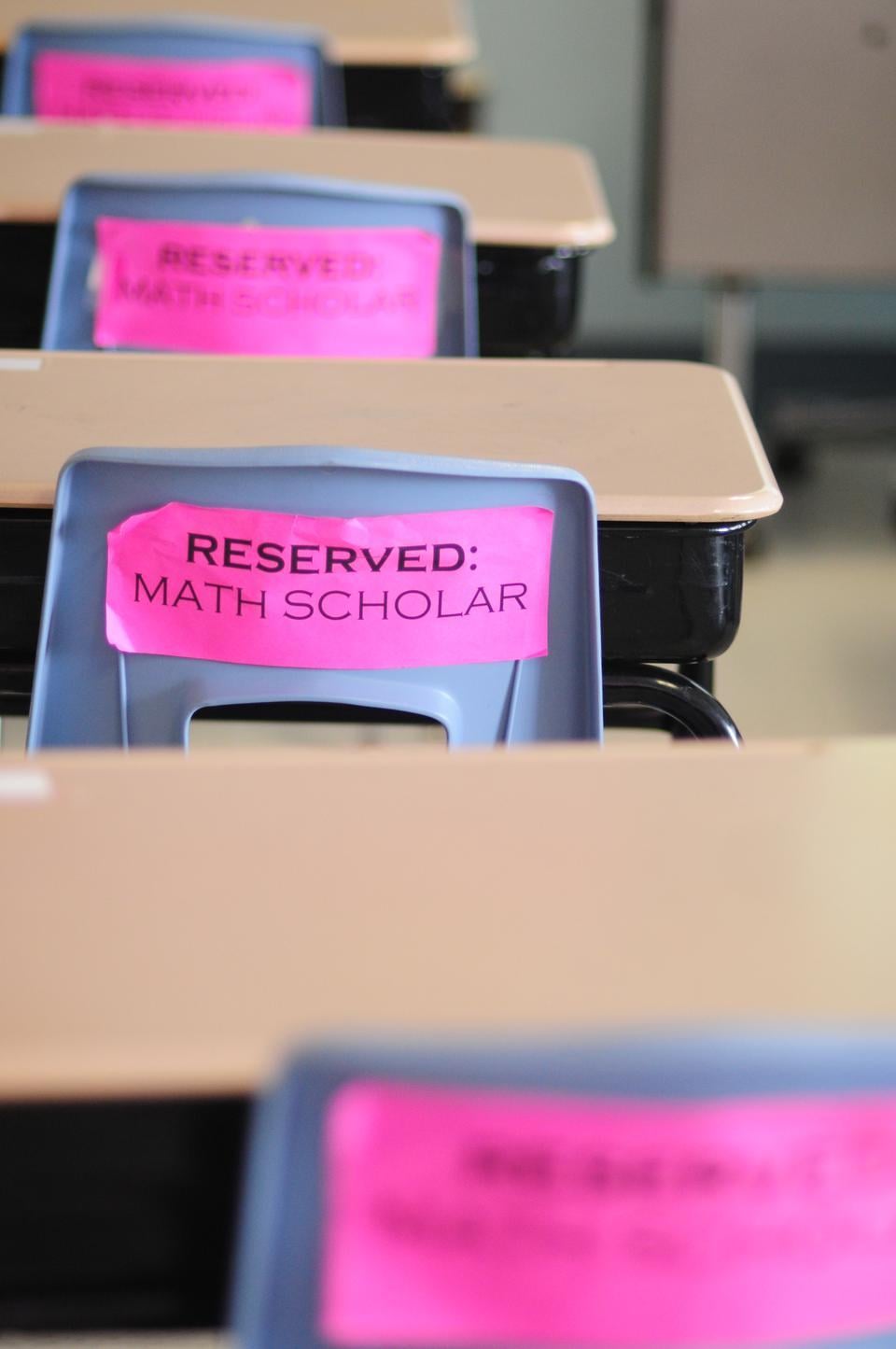 Motivational slogans surround every corner of the classroom, often printed on bright pink paper like these that says, "Reserved: Math Scholar."
