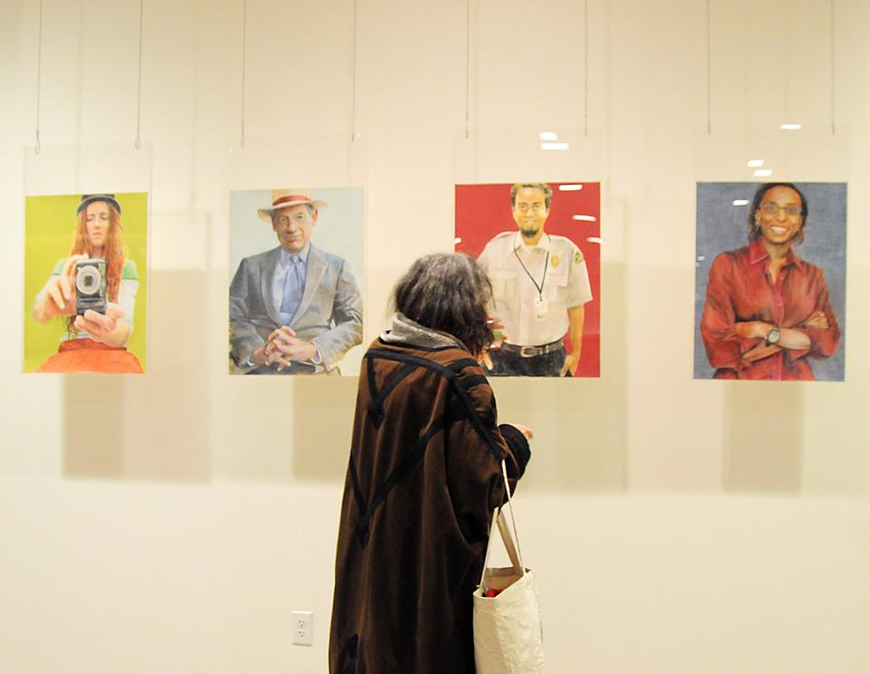 An observer looks on the paintings of artist Bettina Burch displayed in the basement of CGIS South. Bettina's exhibition, Let's Hang Out: Portraits of CGIS, opened yesterday and includes 30 portraits of CGIS staff members, including Burch's self-portrait, pictured above next to a painting of renowned government professor Harvey Mansfield.