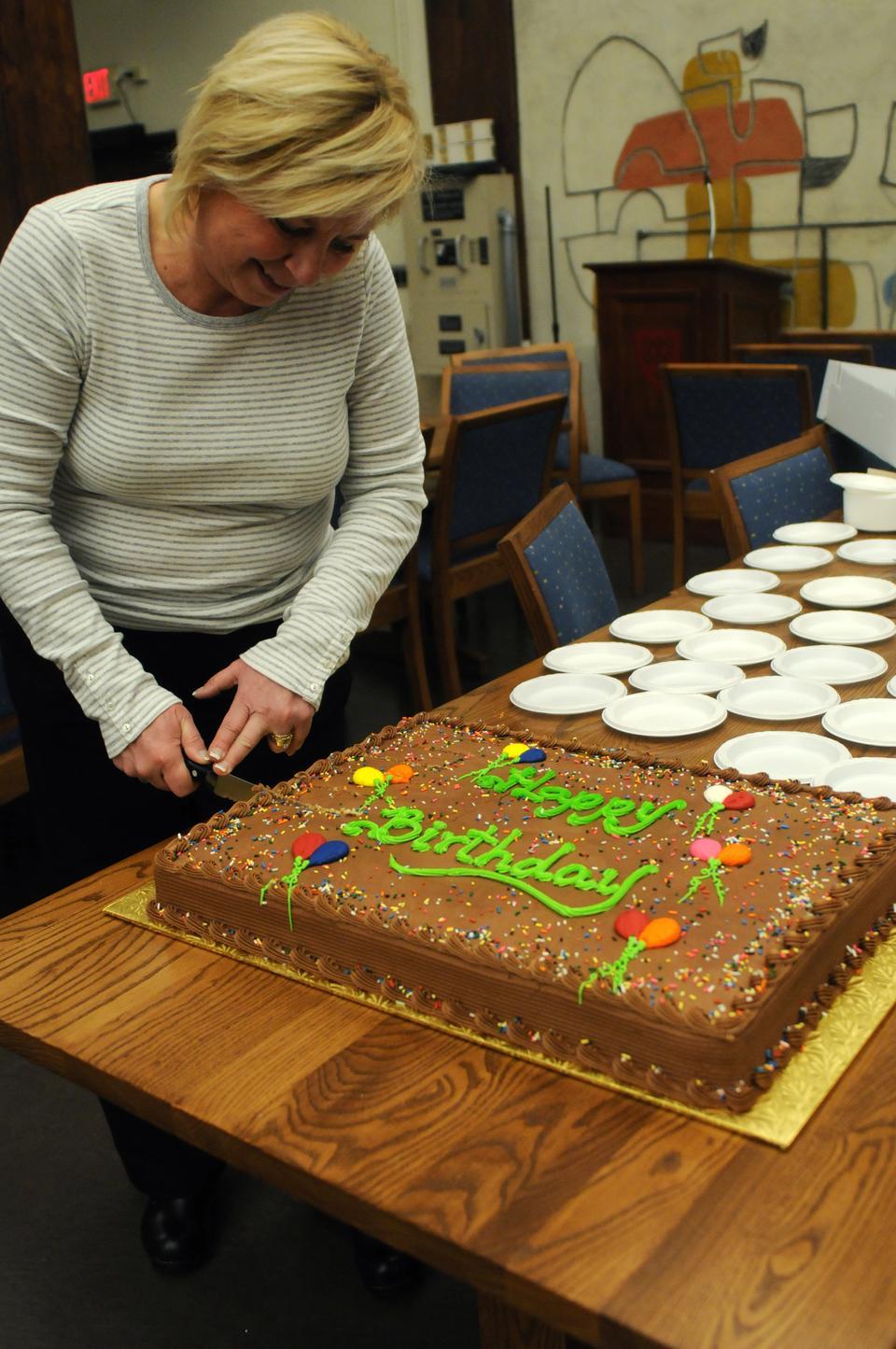 Quincy House Co-Master Deb Gehrke cuts a birthday cake yesterday during Quincy House’s celebration.  