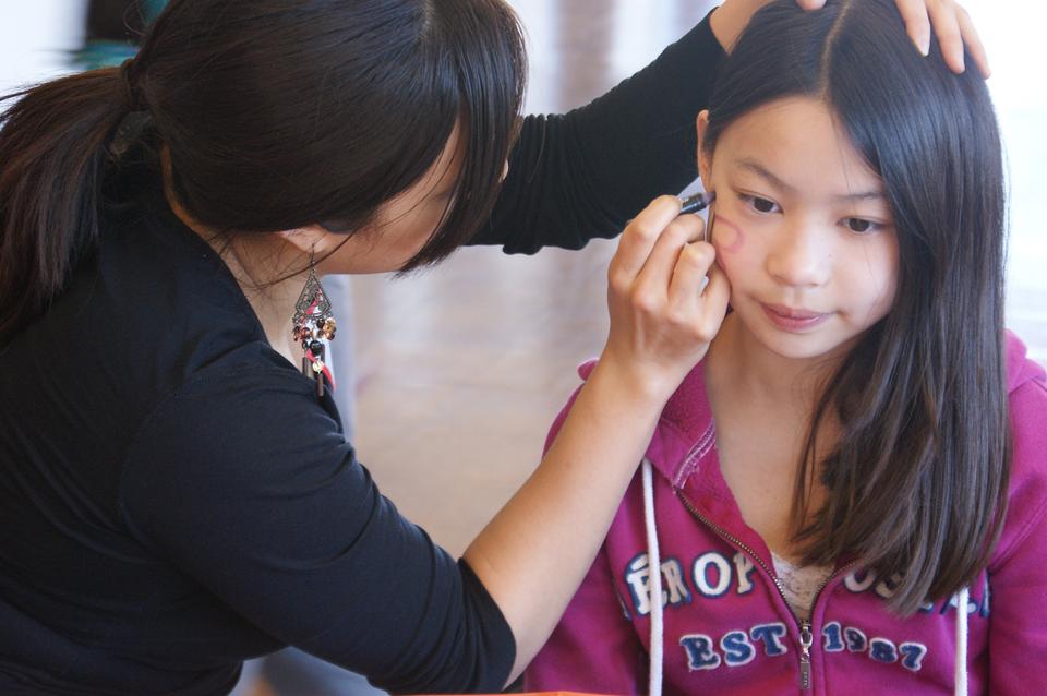 Face painting was only one of many interactive staitons at this weekend's Chinacare Carnival. Florence On paints a purple butterfly for a patient Lily.