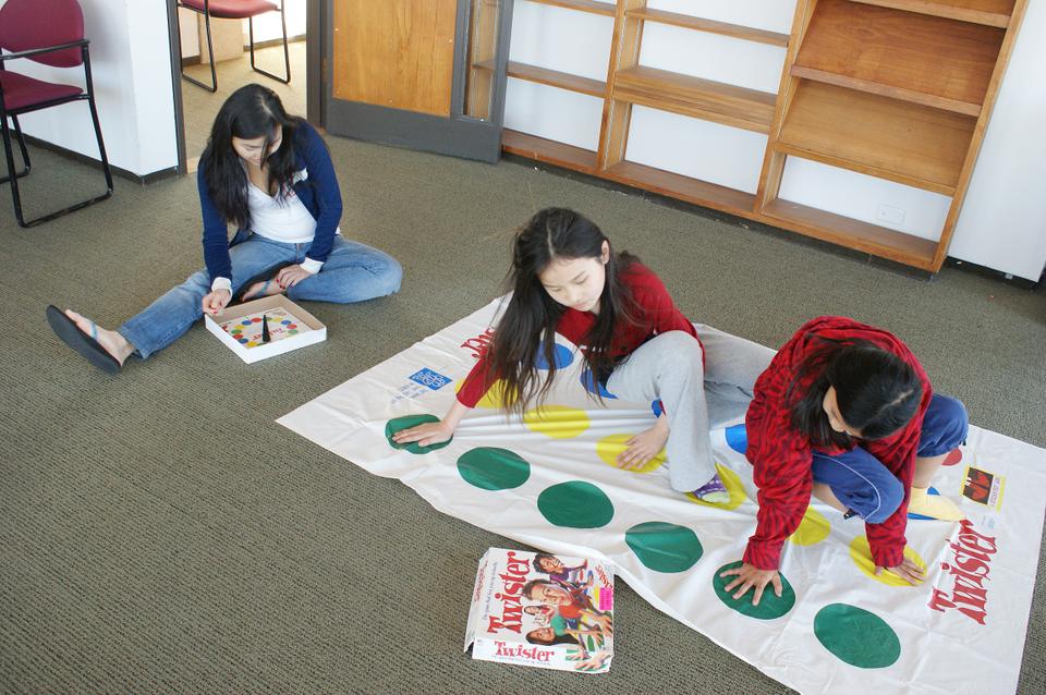 In the Game Room at this weekend's Chinacare Carnival, Jessica Chan calls out colors as Melissa and Emma engage in an intense game of Twister
