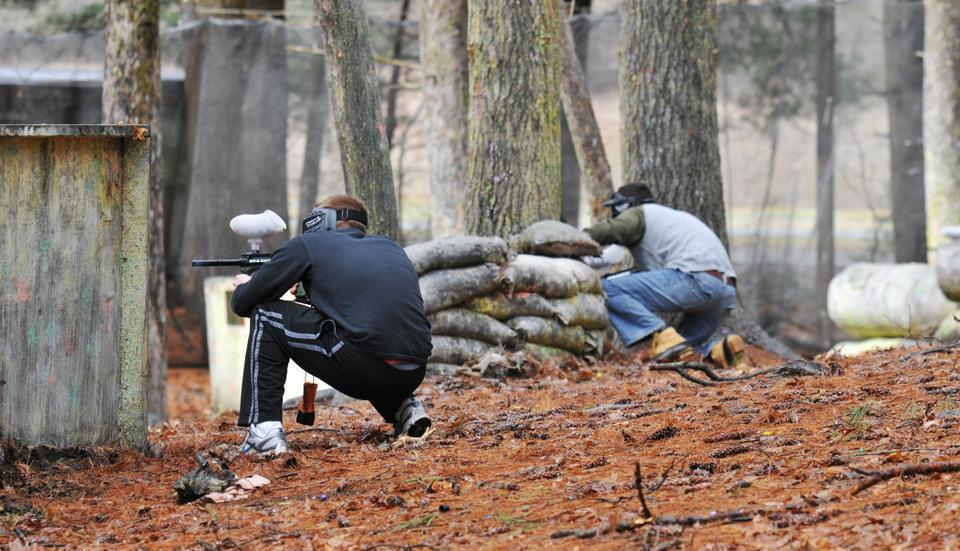 Members of the Harvard Law School Target Shooting Club taking oncoming fire from the Harvard shooting club during a paintball match.