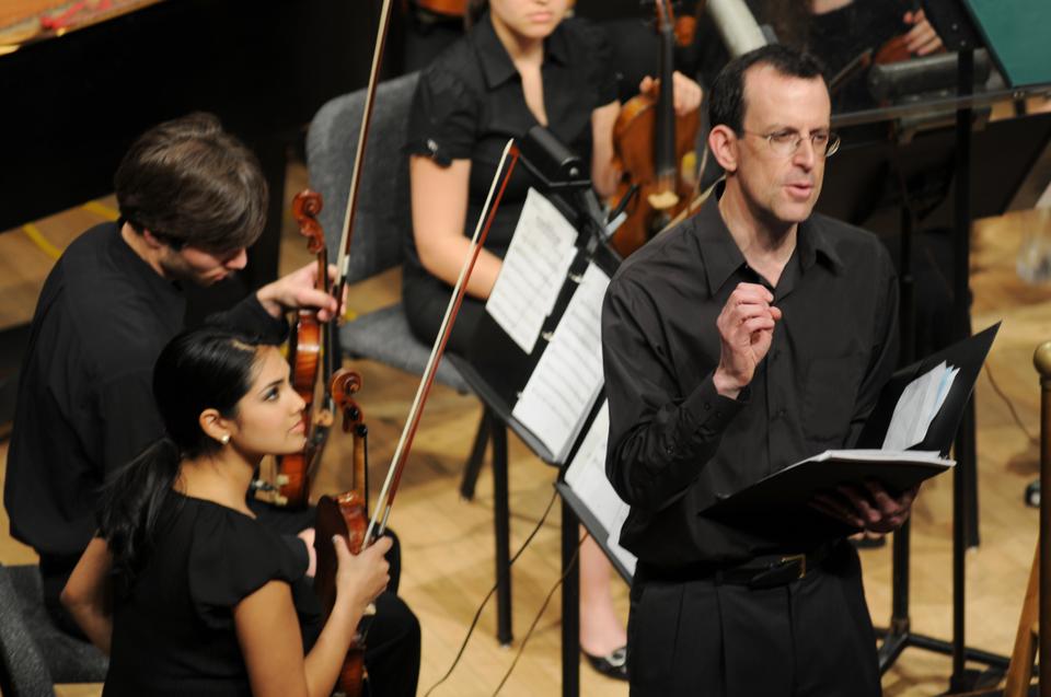 Allen Feinstein '86, music director of Harvard Pops Orchestra, explains the piece "The Voice of the Violin" to an audience in Sanders Theater last night.  Nora Ali '11, left, performed the violin solo.