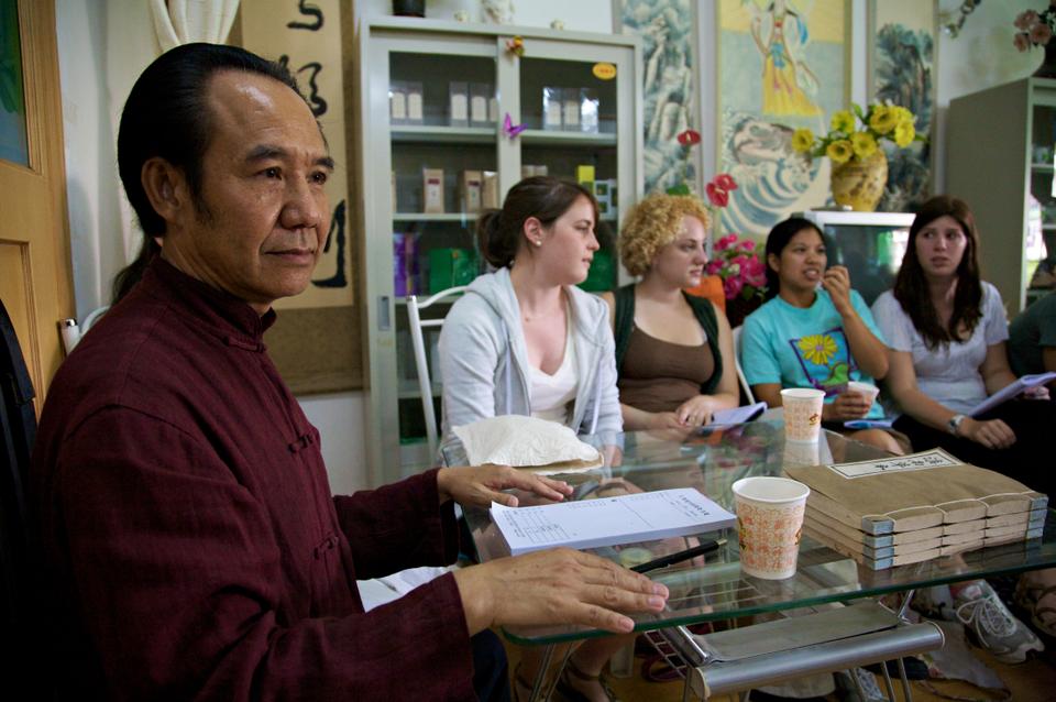 A traditional medicine doctor lectures students on the art-science of pulse reading. From pulses alone, this doctor was able to describe the respiratory, menstrual, and rheumatic ailments afflicting various students pictured.
