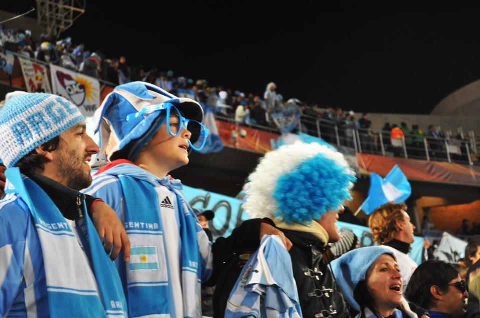 Argentinian fans, decked out in their national team's gear, watch as their team gains advantage over their Greek opponents on June 22nd at the Peter Mokaba Stadium in Polokwane, South Africa.