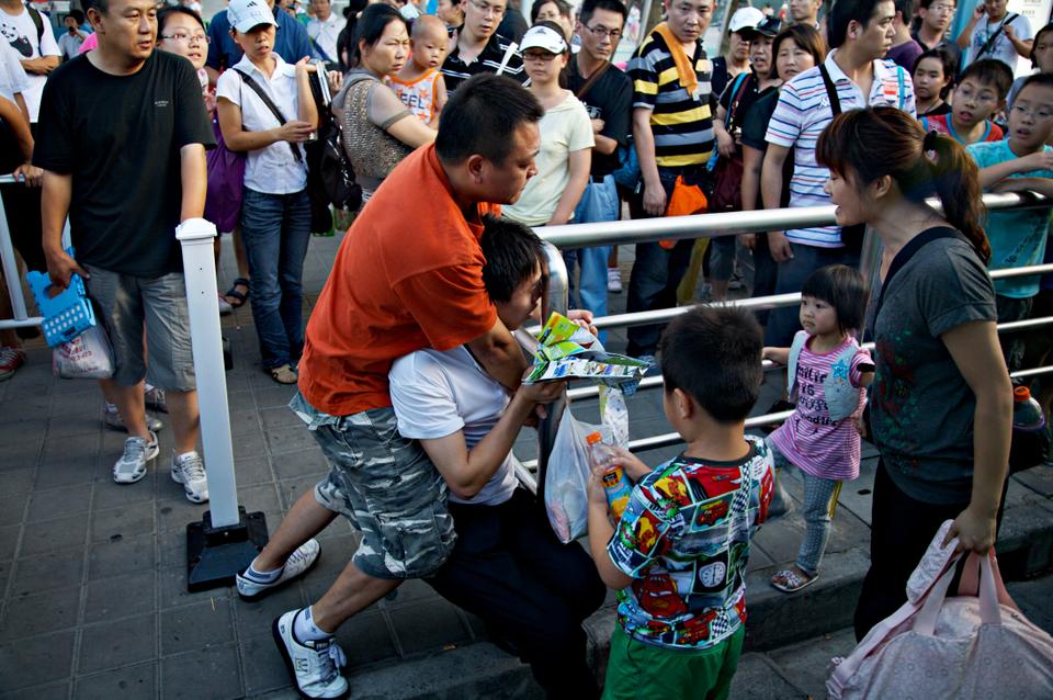 Two men fight at one of the shuttle stops inside the Expo grounds. With lines up to 10 hours long at pavilions such as Saudi Arabia's and with temperatures often rising to 95 degrees Fahrenheit, tempers easily flare.