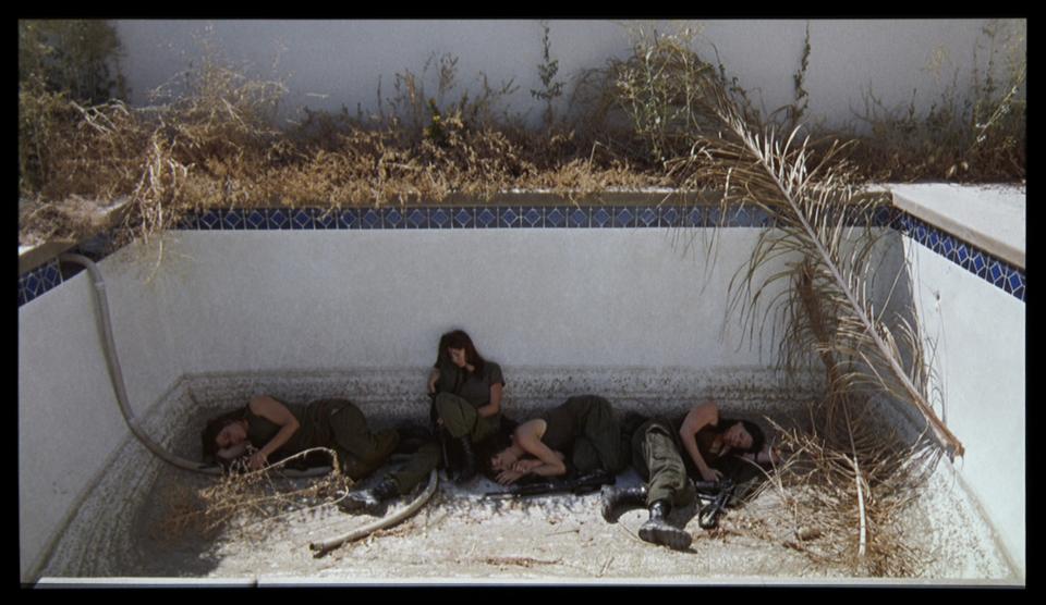 In a scene from Amie Siegel's film, "Black Moon," female revolutionary soldiers take shelter in the ruins of suburban homes. 
