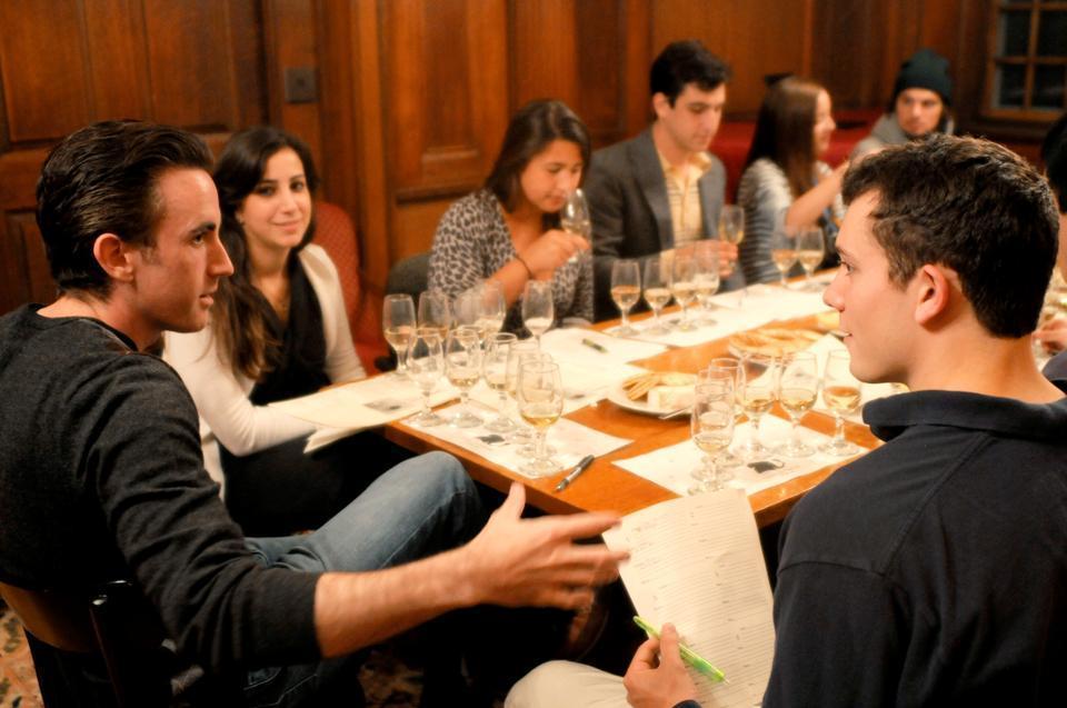 Non-resident tutor Josh Eaton (left) discusses the art of wine with Eliot House students during yesterday's meeting of the Eliot Wine Society. Students gather weekly in the Senior Common Room to sample bottles from across the world. This week's selection included red and white wines from California.