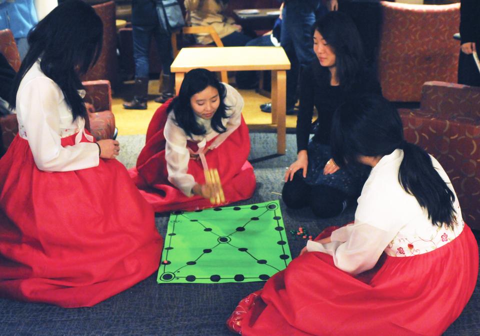 Students sit on the floor to play a Korean tradtional board game during yesterdays Chuseok celebration, hosted by the Korean Association. 
