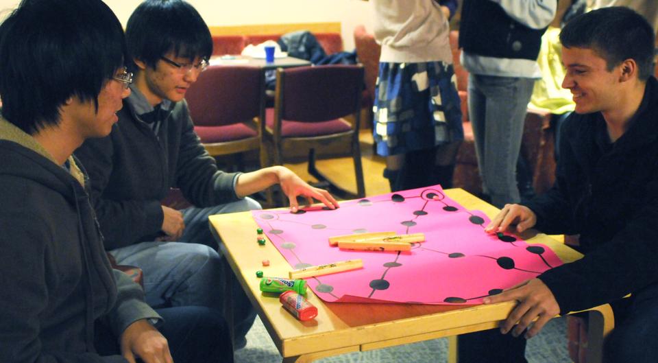 Participants learn how to play Yutnori, a traditional Korean board game involving four wooden sticks, last night in Ticknor Lounge as part of their Chuseok celebration. 