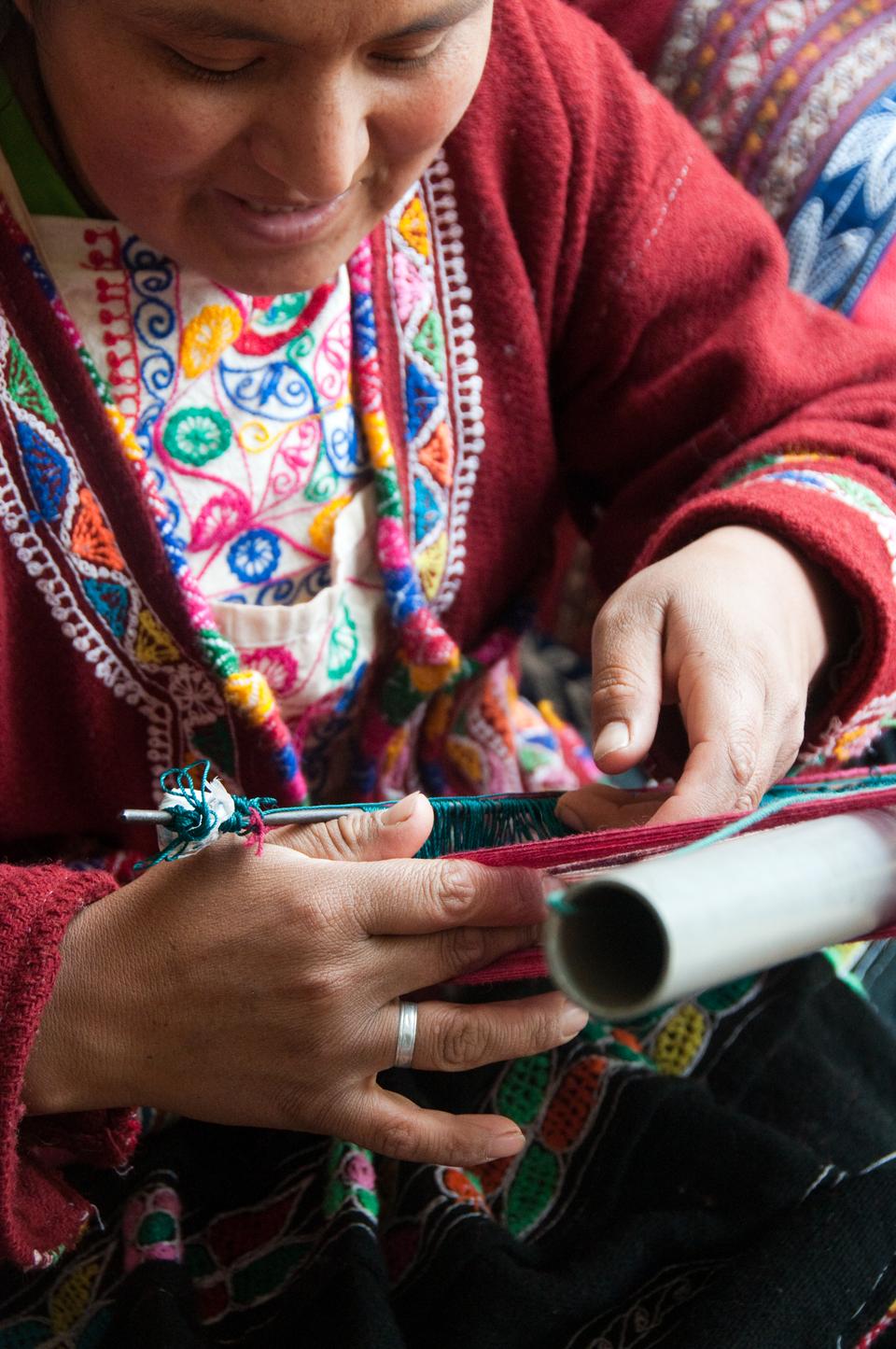 A woman works on a hand-woven tapestry to sell to tourists outside the Inca Museum in Cuzco, Peru. 