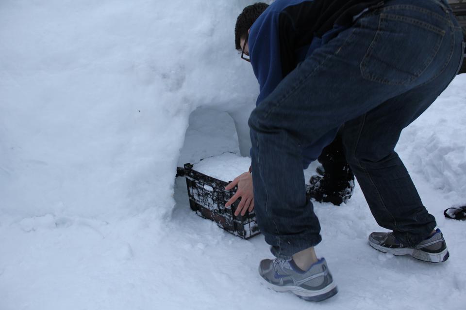 Alex T. Hristov '11 pushes the bricks of ice through the door once the walls were too high to pass them overhead. 