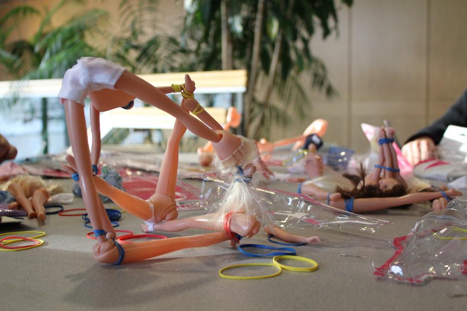Students and Professors experiment with symmetry and geometric shapes using limbs of Barbies in Vi Hart's Playing with Math workshop.