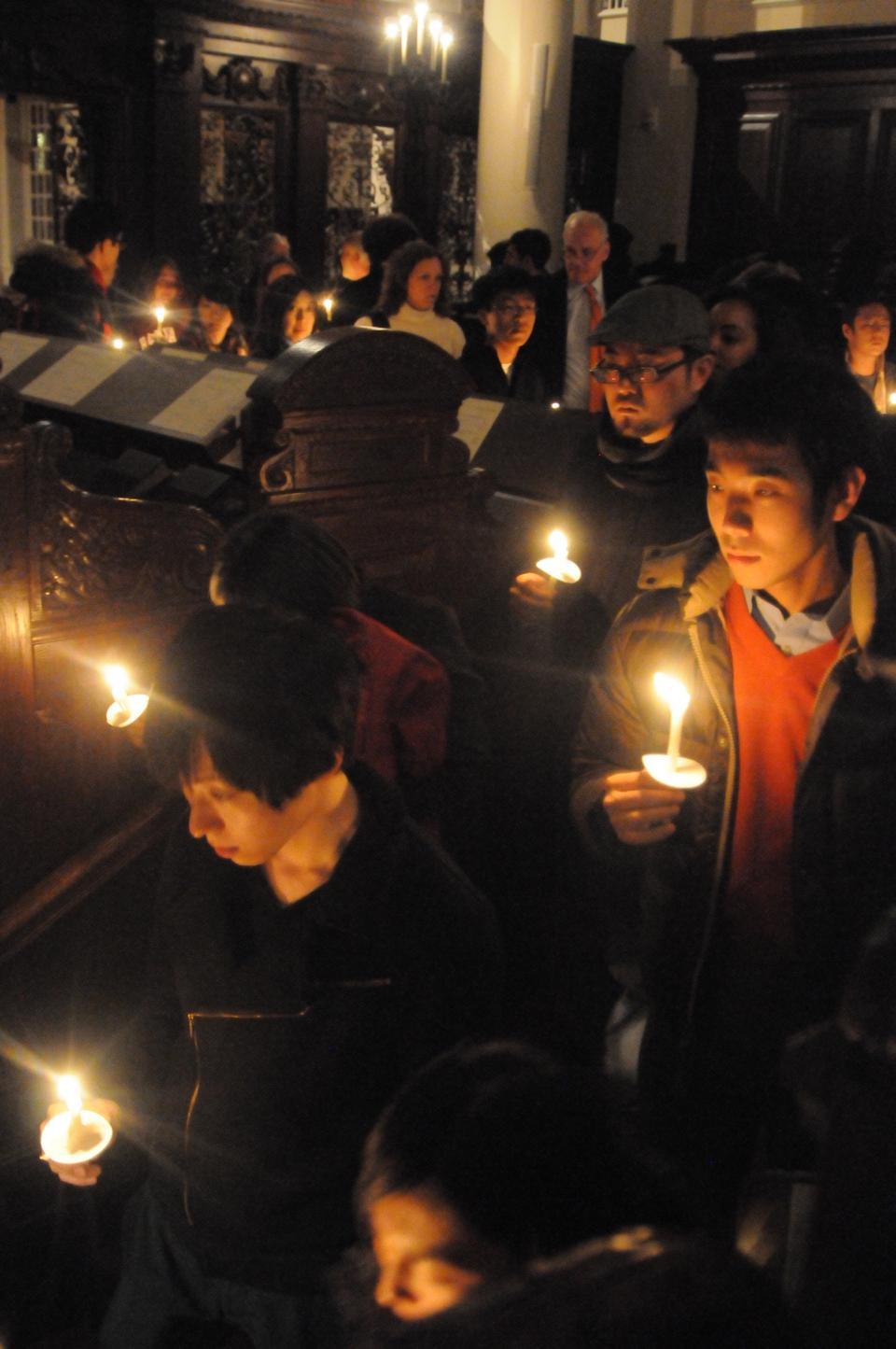 Attendees of a candlelight vigil protect their candle flame as they exit Memorial Church. Yesterday's service recognized those affected by the recent earthquake in Japan.