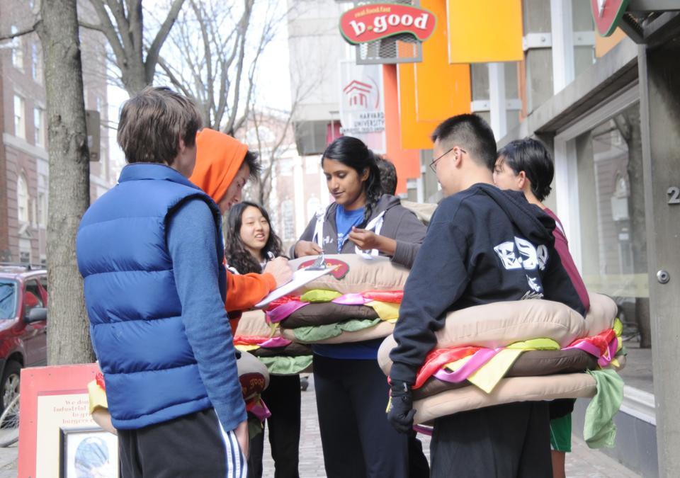 Volunteers sign-up to participate in a community jog called "The Burger Mile" and receive free burgers. Led by the Burger Brigade, they hope to raise money to start a Somerville chapter of "Back On My Feet," an organization that aids Boston's homeless populations.