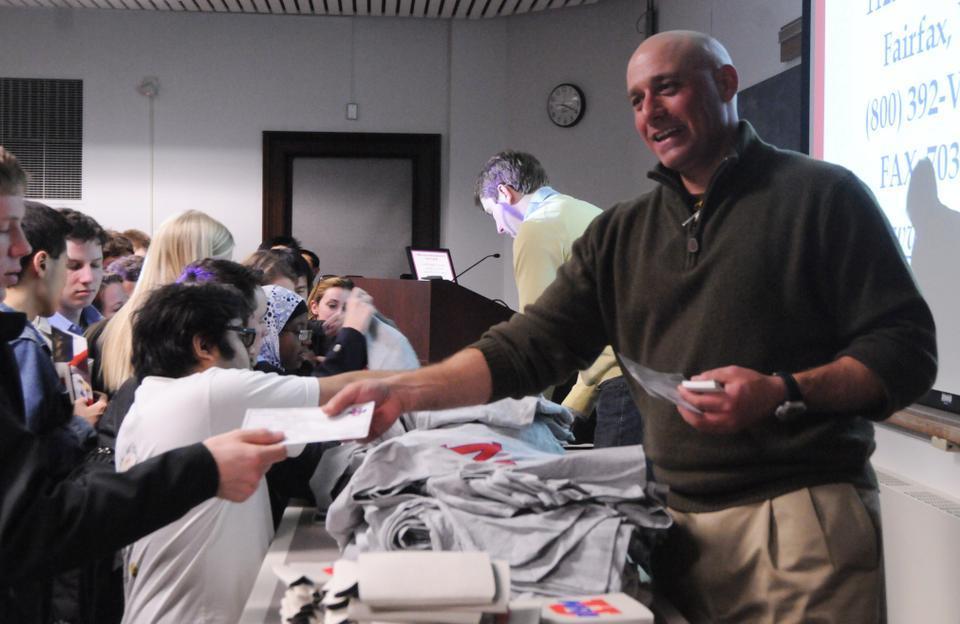 Glen A. Caroline hands out National Rifle Association membership certificates and free t-shirts to students yesterday after his talk on the Second Amendment and gun control. 