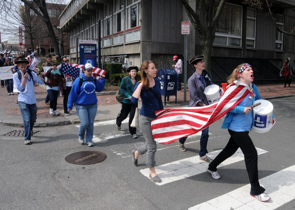 Dozens of protesters participating in the March for Common Sense pass through Harvard Square yesterday as they retrace Paul Revere’s ride from Boston to Lexington in reverse. 
