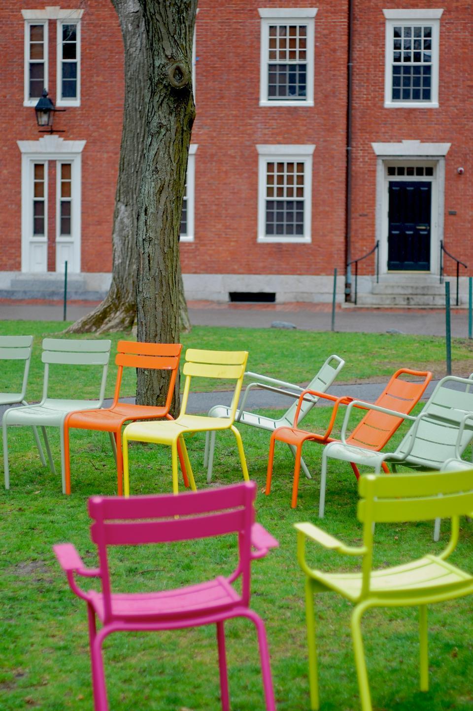 Usually a social space in the center of Harvard Yard, the brightly colored chairs near Stoughton Hall are vacant as students avoid them on a rainy, overcast April afternoon.