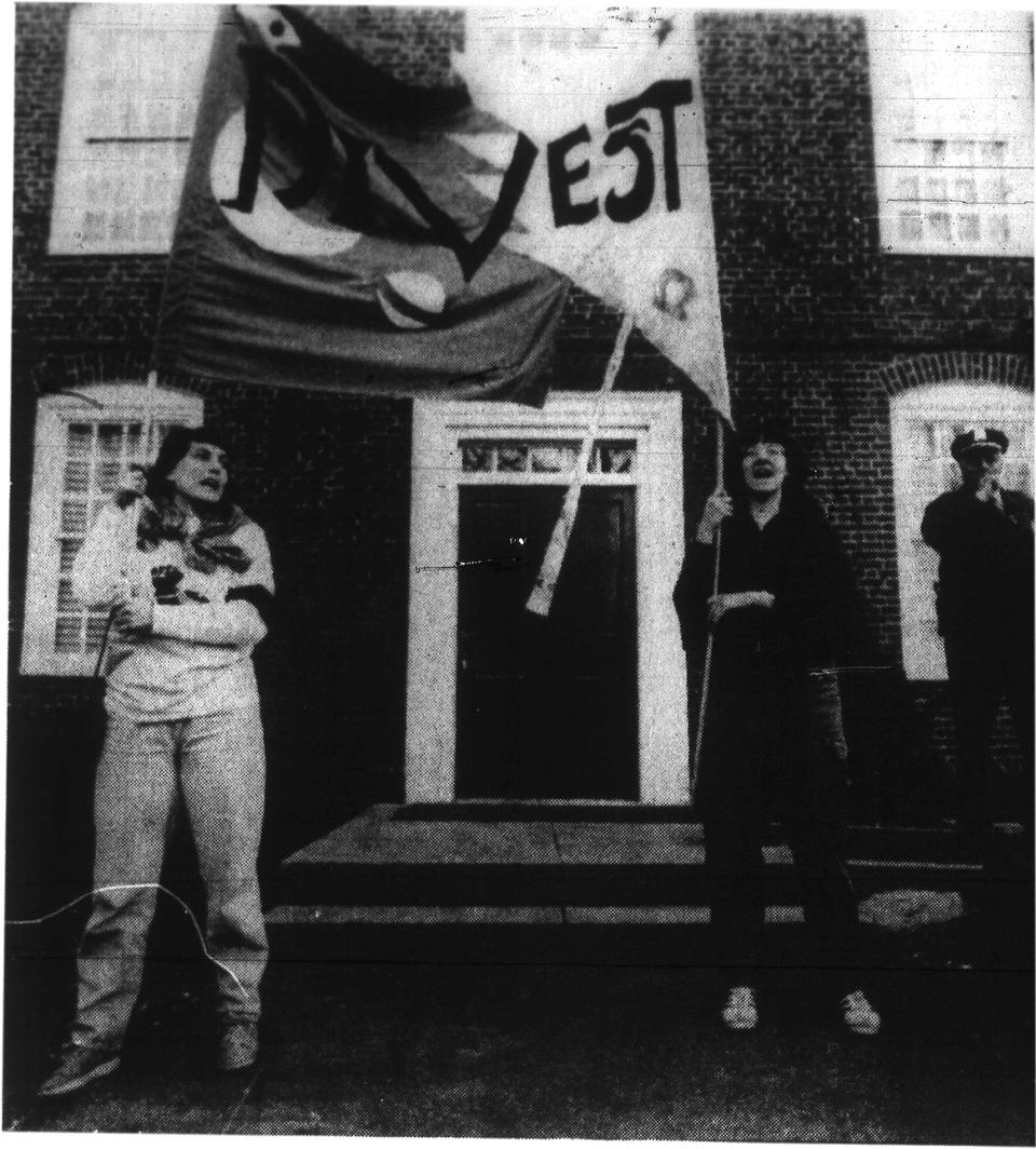 Student protesters wave a banner in front of Mass Hall in 1986 which reads, "Divestment."