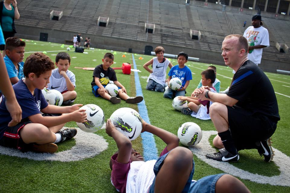 Manchester United Soccer School coach Neil Scott talks to students at Harvard Stadium.