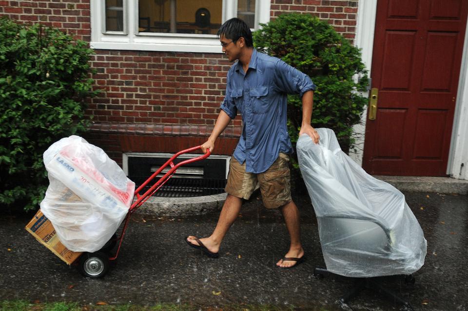 A student tries to keep his belongings dry as he moves into Quincy House on Saturday.