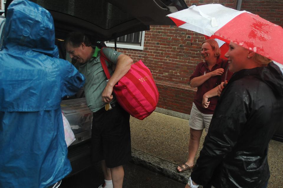 A family moves their daughter into Quincy House in the rain on Saturday.