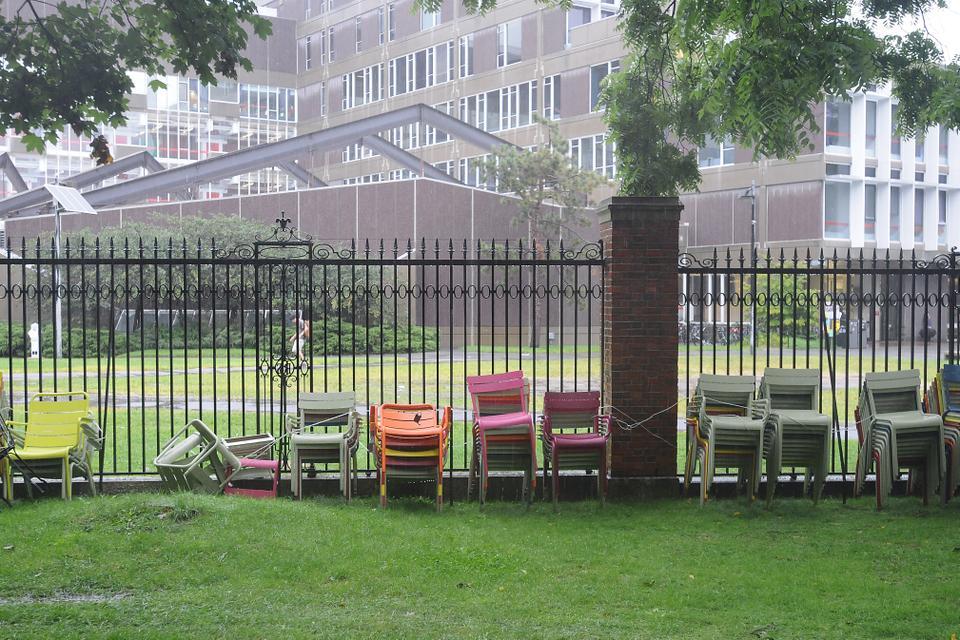 The brightly colored chairs that usually adorn Harvard Yard are stacked against a fence by the Science Center in preparation for Hurricane Irene.