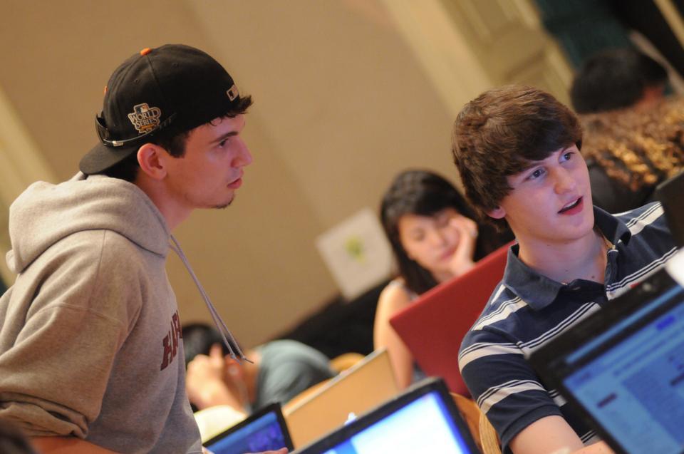 Thomas M. MacWilliam '13. right, and Rob Bowden '13 help students during CS50 office hours using the new computer and app-based interface. CS50 implemented the new program to better serve students.