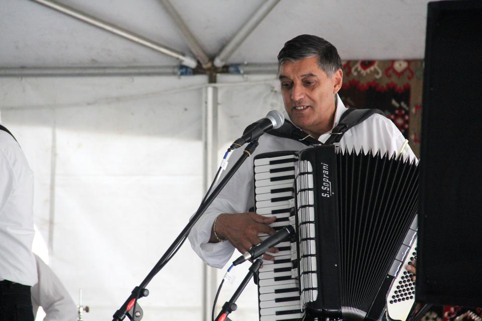 A member of a Serbian band plays traditional music on his accordion in the dining hall while patrons enjoy home cooked food.