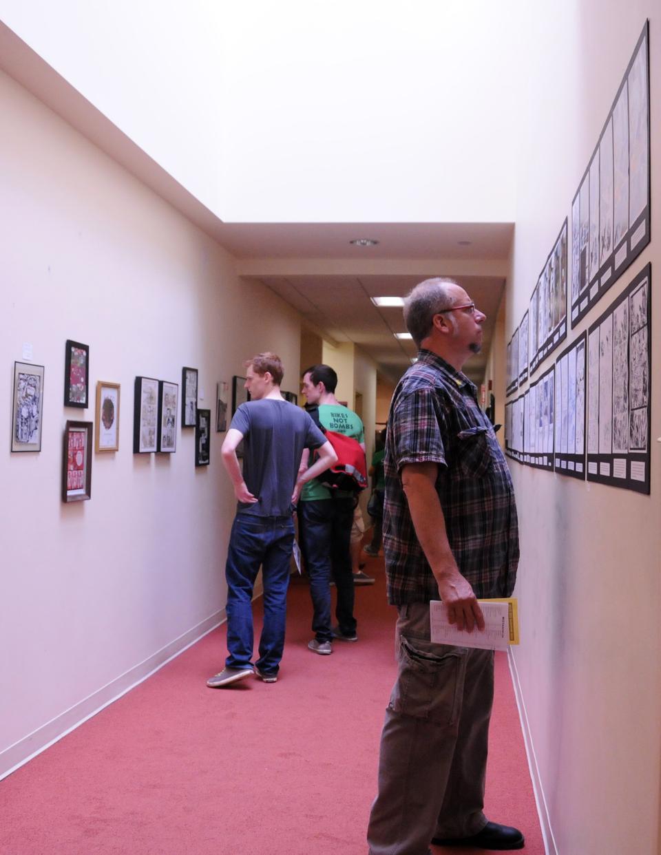 A man reads the comics hung on the wall at the Massachusetts Independent Comics Expo. The expo, which showcased the works of over 100 artists, took place at Lesley Univeristy on Saturday.