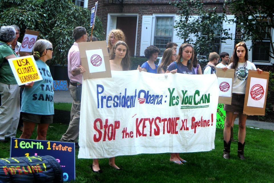 Patricia Levi '12 and Katrina Malakhoff '14 hold up a banner as part of a silent protest to get the attention of David Axelrod on his visit to Harvard. 