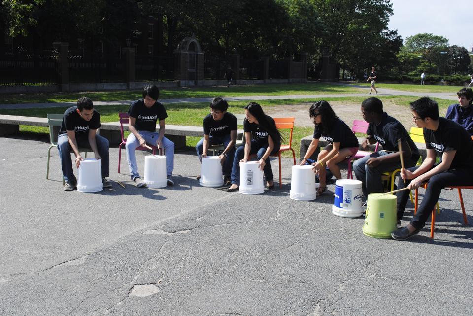 The Harvard Undergraduate Drummers, Harvard’s only percussion ensemble, uses bins to create music in the Science Center Plaza yesterday as part of the “Chairs Revue.”